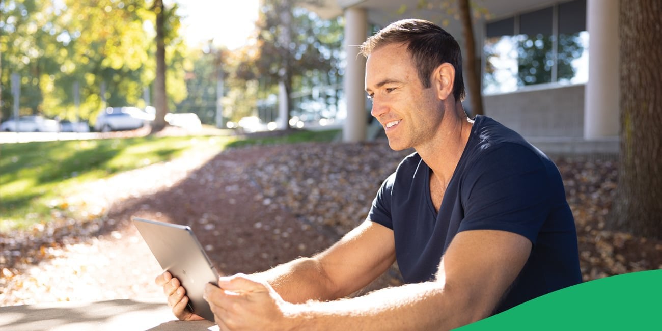 man smiling looking at tablet outdoors