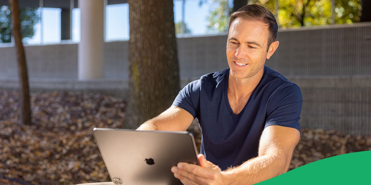 man looking at laptop screen while sitting outside